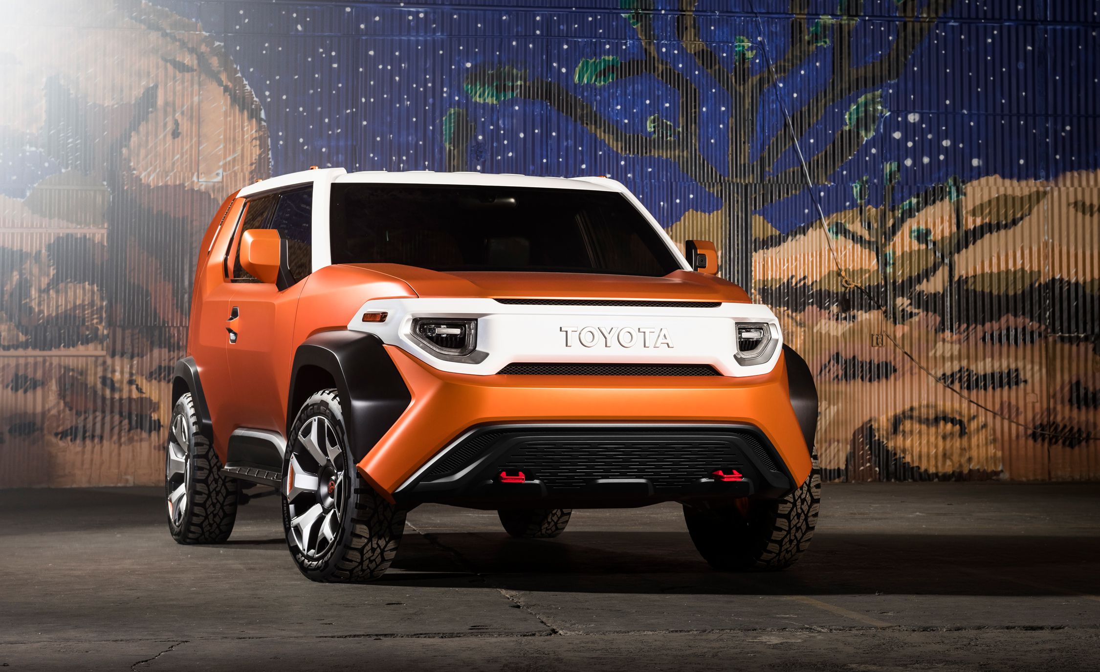 Image of an orange Toyota FT-4X SUV on a stage with a western backdrop.