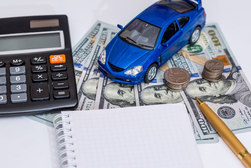 Image of a blue toy car, a notepad, and a calculator on top of $100 bills.