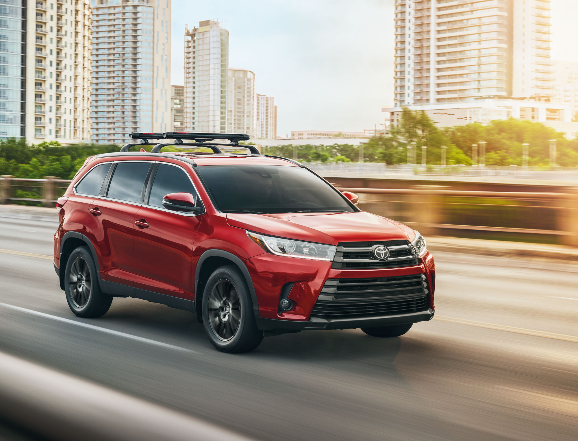 Image of a red 2019 Toyota Highlander driving on a city highway.