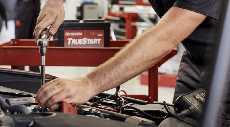 Toyota service technician working on a vehicle battery during auto maintenance