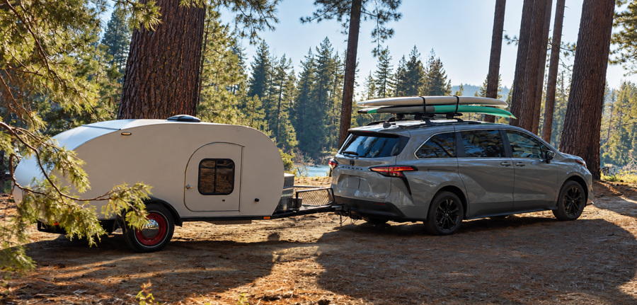 Toyota Sienna towing camper in wooded campsite